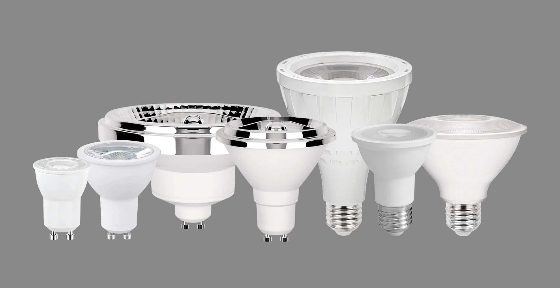 Vária modelos de lâmpadas técnicas (dicroica MR11 e MR16, AR70, AR111, PAR20, PAR30 e PAR30 CDMR) uma ao lado da outra sob fundo cinza